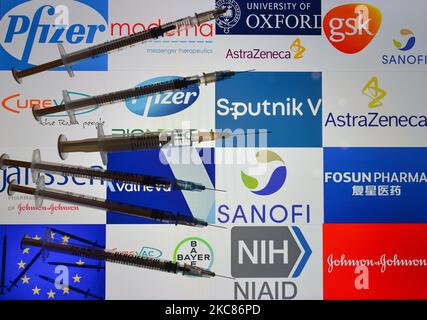 An illustrative image of medical syringes in front of the logos of various companies working on the Covid-19 vaccine, displayed on a screen. On Tuesday, January 26, 2021, in Dublin, Ireland. (Photo illustration by Artur Widak/NurPhoto) Stock Photo