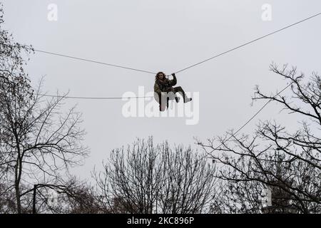 An environmental protester hangs on a zip wire, as police carry out an operation to clear the site of a ‘Stop HS2’ camp at Euston Square Gardens, on 27 January, 2021 in London, England. Despite the evictions, a small group of activists remain inside a tunnel, which was secretly constructed under the site to try to prevent the next phase of work on the high speed rail project set to link London with Birmingham, Manchester and Leeds. (Photo by WIktor Szymanowicz/NurPhoto) Stock Photo