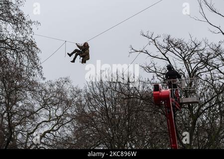 An environmental protester hangs on a zip wire as an officer stands on a cherry picker, during a police operation to clear the site of a ‘Stop HS2’ camp at Euston Square Gardens, on 27 January, 2021 in London, England. Despite the evictions, a small group of activists remain inside a tunnel, which was secretly constructed under the site to try to prevent the next phase of work on the high speed rail project set to link London with Birmingham, Manchester and Leeds. (Photo by WIktor Szymanowicz/NurPhoto) Stock Photo