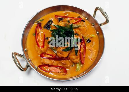 thai style red chicken curry with chili and basil in a serving bowl with white background Stock Photo