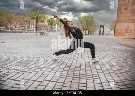 Blonde young woman dressed in black dancing on the street in the rain.dance concept Stock Photo