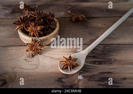 Anise stars (Illicium verum ) in wooden spoon and wooden bowl on dark rustic wooden background. Favorite spice in many food and use for medicine. Frag Stock Photo