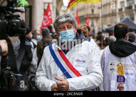 Member of parliament of French leftist La France Insoumise (LFI) party Eric Coquerel (C), wearing a lab coat, talks to the press during a gathering in front of the French pharma giant Sanofi group headquarters in Paris, on February 4, 202, during a day of action to highlight the current economic and cultural difficulties being experienced across France as the coronavirus (Covid-19) pandemic continues. Sanofi, France’s biggest pharmaceutical company and a world leader in vaccine development, announced it plans 1,000 job cuts across France over three years.Sanofi has come under criticism for its Stock Photo