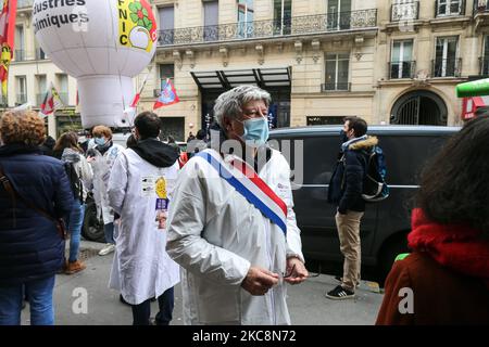 Member of parliament of French leftist La France Insoumise (LFI) party Eric Coquerel (C), wearing a lab coat, talks to the press during a gathering in front of the French pharma giant Sanofi group headquarters in Paris, on February 4, 202, during a day of action to highlight the current economic and cultural difficulties being experienced across France as the coronavirus (Covid-19) pandemic continues. Sanofi, France’s biggest pharmaceutical company and a world leader in vaccine development, announced it plans 1,000 job cuts across France over three years.Sanofi has come under criticism for its Stock Photo