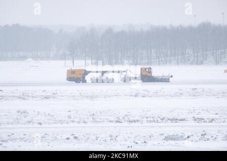 A heavy vehicle is cleaning the runway from the snow. Snowstorm shuts down the airport of Eindhoven EIN in the Netherlands. Heavy snow fall disrupts the air traffic that caused diversions to Germany on Sunday. Blizzard from storm Darcy hit the country since Sunday morning (07.02.2021) resulting problems in public transportation. In the snow-covered Eindhoven airport, Transavia airplanes are seen grounded while heavy machinery is cleaning the taxiway and runway. Dozens of flights that were due to depart were delayed or canceled at Schiphol Airport in Amsterdam due to the arctic cold winter weat Stock Photo