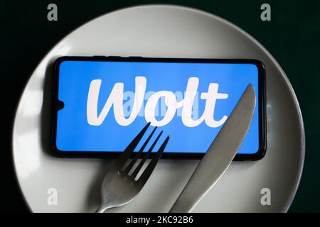 Wolt app logo is displayed on a mobile phone screen photographed for illustration on a plate and with cutlery. Krakow, Poland on February 9, 2021. Numbers show that the Covid-19 pandemic resulted in a significant increase of meals ordered online through food delivery apps and websites. (Photo illustration by Beata Zawrzel/NurPhoto) Stock Photo