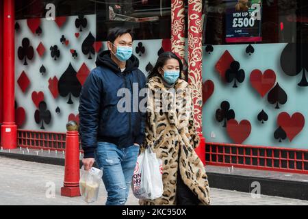 A couple wearing face masks walks in London's Chinatown as the community marks the beginning of the Year of the Ox, on 12 February 2021 in London, England. This year's Chinese New Year festivities in the UK have been cancelled due to coronavirus lockdown restrictions with celebrations taking place online instead. (Photo by WIktor Szymanowicz/NurPhoto) Stock Photo