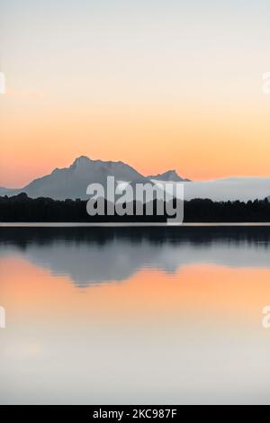 A mountain in the French Alps reflecting in a lake after sunset, minimalism, copy space, soft pastel colours Stock Photo
