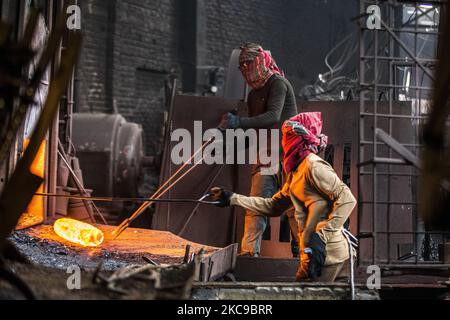 Bangladeshi rolling mill worker seen working in the steel re-rolling mill without proper safety gear or tools in Postagola, Bangladesh on February 15, 2021. In these mills iron is forged in 1200 + to 1300+ Celsius. In such a heated place the soles of their shoes are likely to be burnt off with one careless step. (Photo by Ahmed Salahuddin/NurPhoto) Stock Photo