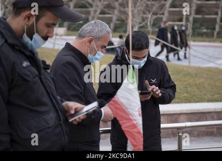 Two men and a park guard use their smartphones after connecting to the 5G network through the Huawei modem in the Water and Fire park in northern Tehran on February 16, 2021. Iran’s first 5G network has ran by the Irancell company which is an Iranian telecommunications company that operates Iran's largest 2G-3G-4G-4.5G also 5G mobile network, and fixed wireless TD-LTE internet services. (Photo by Morteza Nikoubazl/NurPhoto) Stock Photo