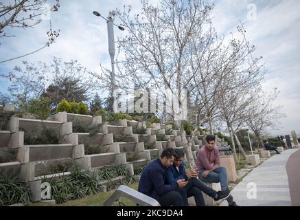 Iranian men use their smartphones as they sit under 5G telecommunications equipment on a MTN-Irancell tower in the Water and Fire park in northern Tehran on February 16, 2021. Iran’s first 5G network has ran by the Irancell company which is an Iranian telecommunications company that operates Iran's largest 2G-3G-4G-4.5G also 5G mobile network, and fixed wireless TD-LTE internet services. (Photo by Morteza Nikoubazl/NurPhoto) Stock Photo
