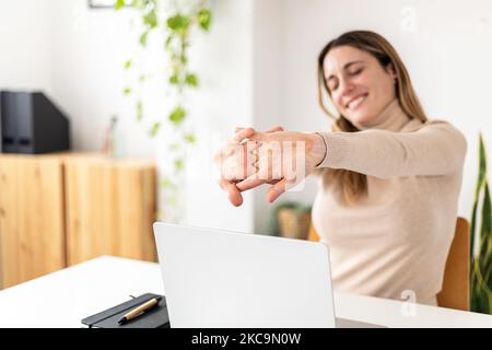 Young businesswoman stretching while sitting at desk in home office Stock Photo