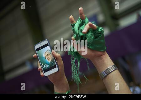 A supporter of the reformist President and 2017 Presidential Election candidate, Hassan Rouhani, holds-up her smartphone as a portrait of the Iranian leader of the opposition in the 2009 post-election unrests, Mir-Hossein Mousavi is seen on its display and green ribbons as she attends the 12000-sit Azadi (Freedom) sport complex during a campaign rally in western Tehran, May 13, 2017. Rouhani re-elected as President of Iran. (Photo by Morteza Nikoubazl/NurPhoto) Stock Photo