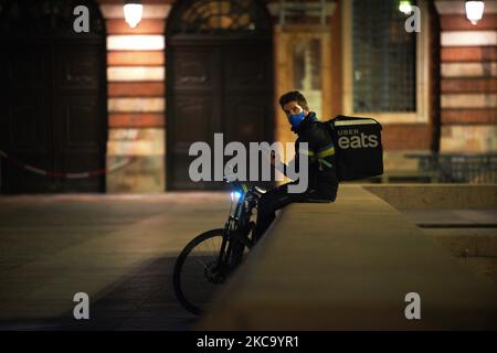 An Uber Eats delivery man waits for orders to deliver during the curfew. Food delivery industry has boomed in the past year as the pandemic forced people to stay at home and shop online as in France where this industry is considered as an 'essential services'. But yesterday Milano prosecutors order food delivery groups to hire riders, pay 733 million euros in fines after an investigation showed their working conditions were inadequate. The European Commission took a step towards improving the rights of gig economy workers with the launch of a public consultation to determine their legal employ Stock Photo