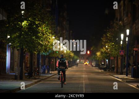 An Uber Eats rider cycles in an empty street during the Covid-19 curfew. Food delivery industry has boomed in the past year as the pandemic forced people to stay at home and shop online as in France where this industry is considered as an 'essential services'. But yesterday Milano prosecutors order food delivery groups to hire riders, pay 733 million euros in fines after an investigation showed their working conditions were inadequate. The European Commission took a step towards improving the rights of gig economy workers with the launch of a public consultation to determine their legal employ Stock Photo