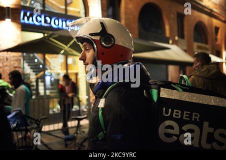 An Uber Eats worker wait in front of a McDonalds for his oder. Food delivery industry has boomed in the past year as the pandemic forced people to stay at home and shop online as in France where this industry is considered as an 'essential services'. But yesterday Milano prosecutors order food delivery groups to hire riders, pay 733 million euros in fines after an investigation showed their working conditions were inadequate. The European Commission took a step towards improving the rights of gig economy workers with the launch of a public consultation to determine their legal employment statu Stock Photo