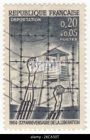 FRANCE - 1964  March 21: An 20 centimes plus 5 centimes slate-black Semi-Postal stamp depicting “Deportation”, concentration camp with watchtower and barbed wire. 20th anniversary of liberation from the Nazis Stock Photo