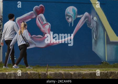 A couple walks by the mural by artist Magdalena Karol seen in Dublin's Grand Canal area. On Monday, 8 March, 2021, in Dublin, Ireland. (Photo by Artur Widak/NurPhoto) Stock Photo