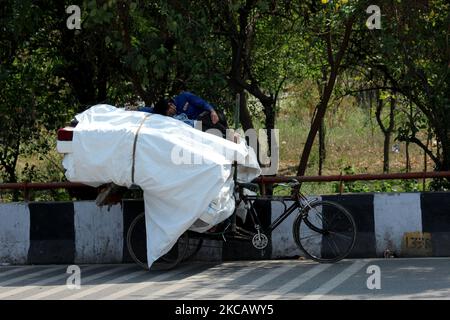 An Indian rickshaw puller takes a break as he sleeps over the goods loaded on his rickshaw on a hot day in New Delhi, India on March 14, 2021. (Photo by Mayank Makhija/NurPhoto) Stock Photo