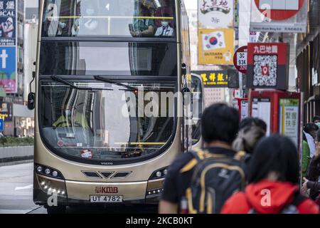 Commuters wait for buses at a bus station as a bus operated by KMB Drives pass in Hong Kong, Tuesday, March 13, 2021. Today the Hong Kong Government Executive Council approve Fare Increase for Hong Kongâ€™s Major Bus Company , Citybus and New World First Bus, which are both owned by Bravo Transport, to increase fares in two phases â€“ by 8.5 per cent from April 4 and a further 3.2 per cent on January 2 next year.KMB was allowed to raise fares by 8.5 per cent, while New Lantao Bus can charge passengers 9.8 per cent more, both effective on April 4. (Photo by Vernon Yuen/NurPhoto) Stock Photo