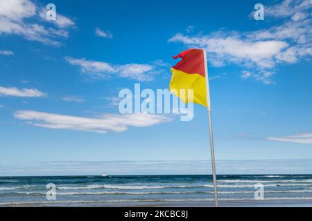 Red and Yellow Life Saving Flag on Gold Coast Beach Stock Photo