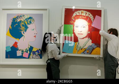 Art handlers poses holding 'Queen Elizabeth II, from: Reigning Queens (Royal Edition)' (R), by American artist Andy Warhol, estimated at GBP100,000-150,000, and beside one of Warhol's set of four 'Queen Margarethe II of Denmark, from: Reigning Queens (Royal Edition)', estimated at GBP60,000-80,000, during a press preview at Christie's auction house in London, England, on March 26, 2021. (Photo by David Cliff/NurPhoto) Stock Photo