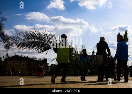 People carry palm leaves on Palm Sunday in Krakow, Poland on March 28, 2021. During Palm Sunday, which is also called The Sunday of the Lord's Passion, participants traditionally attend a Holy Mass and walk in the procession carrying handwoven palms, however this year, due to the coronavirus pandemic, restrictions allowed a limited number of people participate inside churches. (Photo by Beata Zawrzel/NurPhoto) Stock Photo