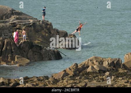 Young swimmers jump into the water at Forty Foot in Sandycove, Dublin, in fine sunny weather during level 5 COVID-19 lockdown. On Tuesday, March 30, 2021, Sandycove, Dublin, Ireland. (Photo by Artur Widak/NurPhoto) Stock Photo