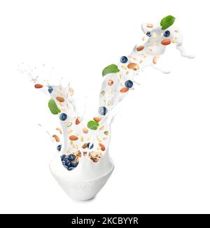 Bowl with splashing milk, sweet oatmeal, falling blueberries and nuts on white background Stock Photo