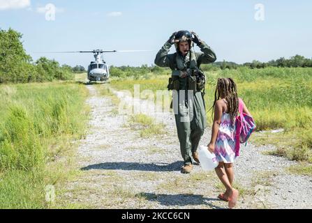 A U.S. Marine leads a child to a UH-1Y helicopter during a Hurricane Harvey rescue mission. Stock Photo
