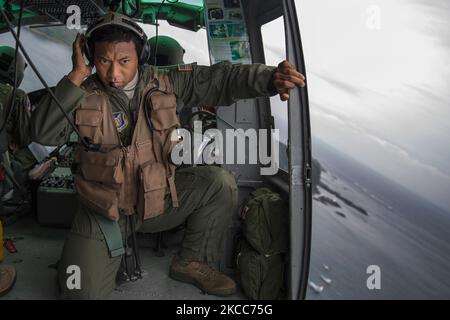 An airman listens to the radio in a UH-1N Iroquois over Japan. Stock Photo