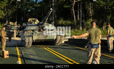 An M1A1 Abrams tank is guided onto an M17 floating raft. Stock Photo