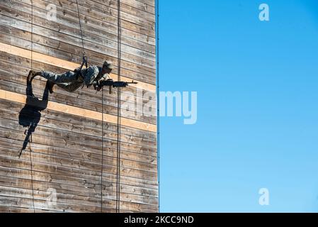A U.S. Army Ranger carrying an M249 light machine gun rappels down a wall. Stock Photo
