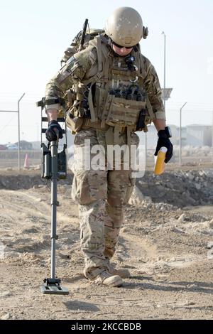 An explosive ordnance disposal technician uses a flashlight to inspect ...