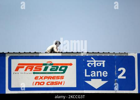 A worker gives the final touches to the roof of a toll plaza with FASTag facility, at KMP Expressway in Ghaziabad on the outskirts of New Delhi, India on April 10, 2021. FASTag is an electronic toll collection system in India, operated by the National Highway Authority of India (NHAI). (Photo by Mayank Makhija/NurPhoto) Stock Photo