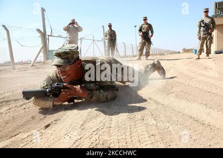 A U.S. Army soldier smiles as he demonstrates how to high crawl with weapons. Stock Photo