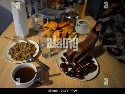 Ifrah Ahmed, a Somali-Irish living in Dublin, breaks the fast with the iftar, a traditional opening of the meal by eating three dates and having a glass of water inside her apartment, on the second day of Ramadan, during the COVID-19 lockdown. Ramadan is known for the element of fasting. Muslims fast from dawn until dusk. An individual participating in the Ramadan celebration will only partake in two meals per day - suhour (meal eaten before sunrise) and iftar (after sunset, the meal that ends the fast). Due to the engoing lockdown restrictions and closures, all religious sites remain closed i Stock Photo