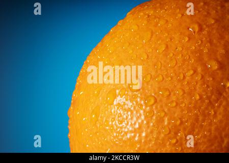 Fresh orange fruit skin close up. Ripe orange texture with water drops on blue background. Banner Stock Photo