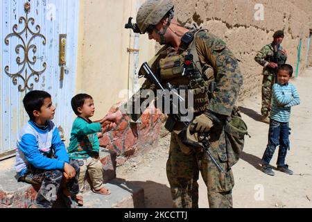 A U.S. Marine shakes hands with an Afghan child. Stock Photo
