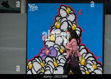 A couple wearing face masks walks past a mural by Pens in Rathmines, Dublin, during the COVID-19 lockdown. On Friday, 16 April 2021, in Dublin, Ireland. (Photo by Artur Widak/NurPhoto) Stock Photo