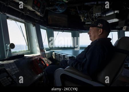 Commanding officer of guided missile destroyer USS Carney sits in the pilot house. Stock Photo