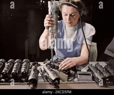 Woman worker using an electric screwdriver to assemble toy trains, 1942. Stock Photo