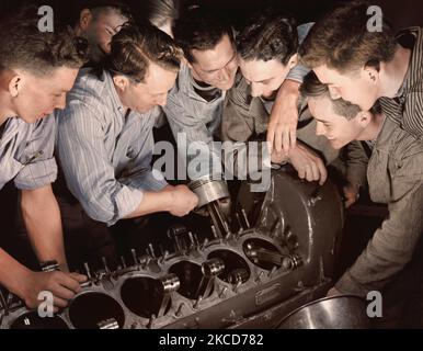 Instructor showing a group of men how to assemble an airplane engine. Stock Photo