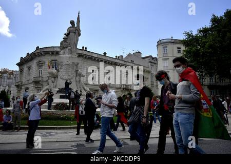Attendants of the April 25th parade wearing protective masks and carrying Portuguese flags walk near the Heroes of the Great War Monument , in Lisbon, Portugal, on April 25, 2021. After 1 year without commemorating the traditional parade in commemoration of the overthrow of the dictator Antonio de Oliveria Salazar in 1974, the Portuguese government has given authorization for the celebration of what is called The Carnation Revolution, which circulated through the main streets of the Portuguese capital. (Photo by Jorge Mantilla/NurPhoto) Stock Photo