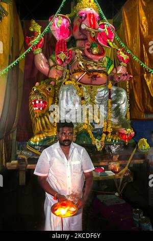 Tamil Hindu priest performs prayers by a large clay idol of Lord Ganesha (Lord Ganesh) at a pandal (temporary shrine) along the roadside during the festival of Ganesh Chaturthi in Kuttalam, Tamil Nadu, India. Ganesh Chaturthi (also known as Vinayaka Chaturthi) is a Hindu festival celebrating the arrival of Ganesh to earth from Kailash Parvat with his mother Goddess Parvati. (Photo by Creative Touch Imaging Ltd./NurPhoto) Stock Photo