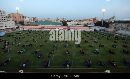 Palestinians break their Ramadan fast during an Iftar meal set-up to respect social distancing measures amid the COVID-19 pandemic, organized by the Islamic Hamas movement which runs the besieged Gaza Strip, at the Palestine football stadium in Gaza city on May 6, 2021, ahead of launching a digital campaign to mark al-Quds (Jerusalem) international day. - While Israelis celebrate their 1967 capture of the eastern part of the holy city, Palestinians commemorate the day with events marking the Palestinian and Muslim connection to the holy city. (Photo by Majdi Fathi/NurPhoto) Stock Photo