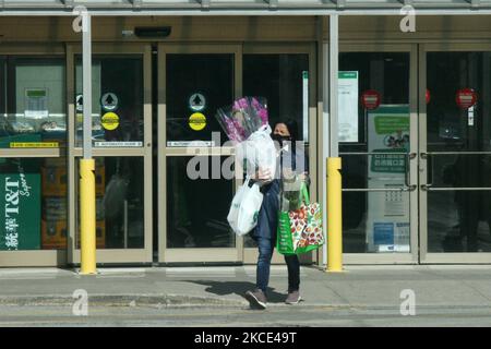 Woman wearing a face mask during the novel coronavirus (COVID-19) pandemic while carrying orchid plants she had purchased for the upcoming Mother's Day weekend in Toronto, Ontario, Canada on May 06, 2021. Ontario has been placed under another stay-at-home order amid surging COVID-19 case. The Order will also order the closure of all non-essential retail outlets for in-person shopping and will be accompanied by Ontario's third state of emergency declaration since the beginning of the pandemic. (Photo by Creative Touch Imaging Ltd./NurPhoto) Stock Photo
