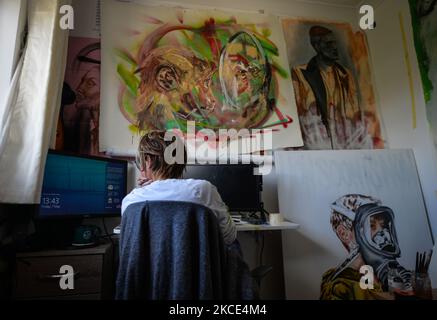 Chelsea Jacobs aka Chels, an American artist living in Dublin, gets ready to work in front of the computer after lunch break while working on an oil painting of a man feeding pigeons in St Stephen's Green, Dublin. During the long months of the lockdown, Chelsea worked from home, in her office/studio, which served as an online workspace at the bank and as an art studio during lunchtime breaks and after work. On Friday, 7 May 2021, in Dublin, Ireland. (Photo by Artur Widak/NurPhoto) Stock Photo