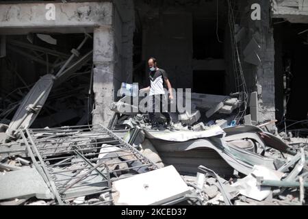 A Palestinian man walks at the rubble of the severely damaged Al-Jawhara Tower in Gaza City on May 12, 2021 after it was hit by Israeli airstrikes amid the escalating flare-up of Israeli-Palestinian violence. The Health Ministry in the Hamas-run Gaza Strip said the number of Palestinians killed has risen to 35, including 12 children, while 233 people were reported injured. (Photo by Momen Faiz/NurPhoto) Stock Photo