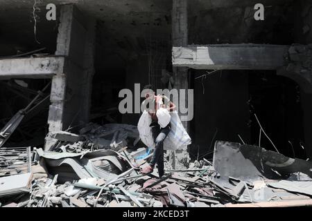 A Palestinian man walks at the rubble of the severely damaged Al-Jawhara Tower in Gaza City on May 12, 2021 after it was hit by Israeli airstrikes amid the escalating flare-up of Israeli-Palestinian violence. The Health Ministry in the Hamas-run Gaza Strip said the number of Palestinians killed has risen to 35, including 12 children, while 233 people were reported injured. (Photo by Momen Faiz/NurPhoto) Stock Photo